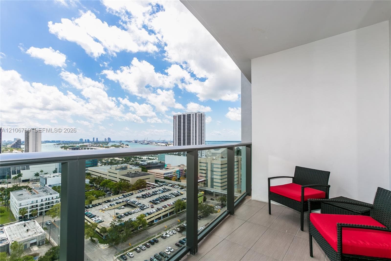 Private balcony featuring neutral-toned floor tile and a dark metal railing with clear glass panels