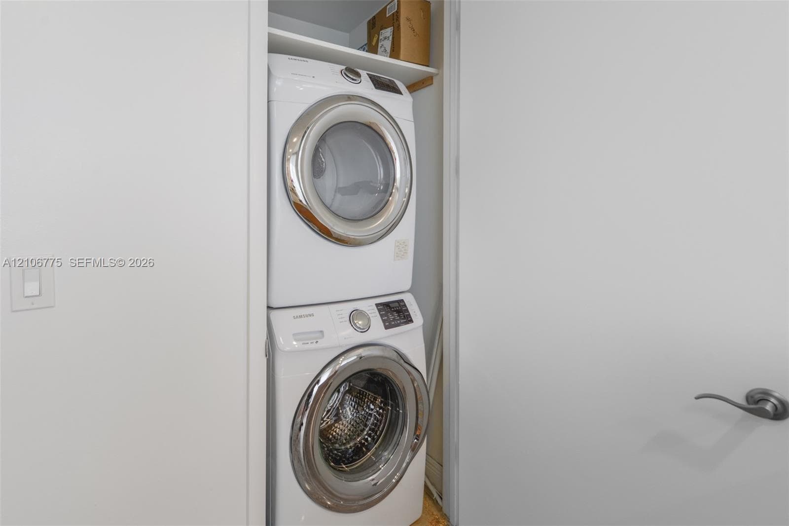 Stacked front-loading washer and dryer unit with built-in overhead shelving housed within a dedicated closet
