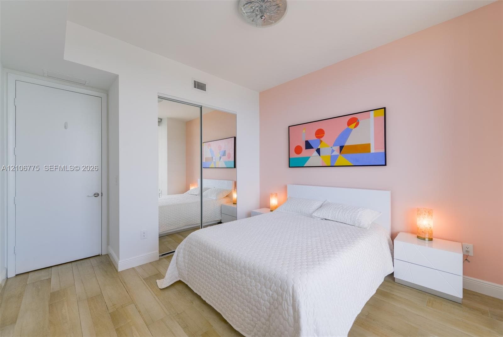 Interior room featuring wood-finish flooring, sliding mirror-panel closet doors, and flush-mount ceiling lighting