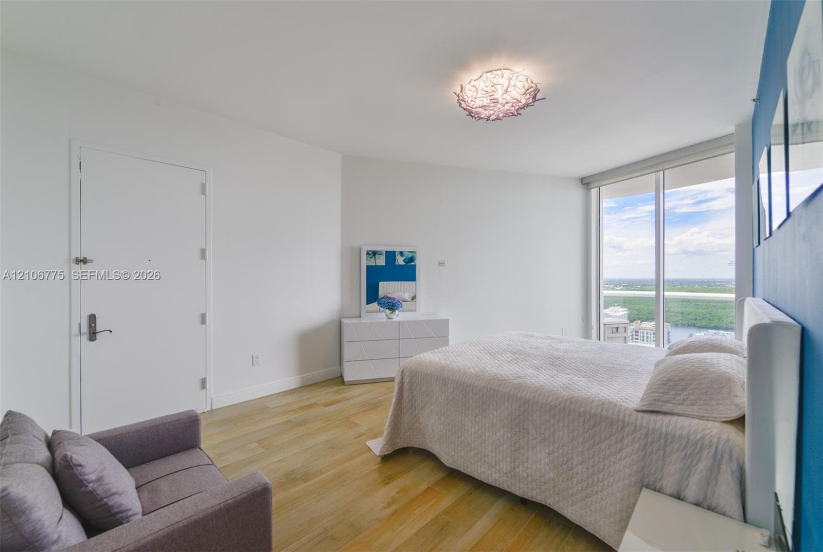 Floor-to-ceiling windows, wood-finish flooring, and decorative flush-mount ceiling lighting