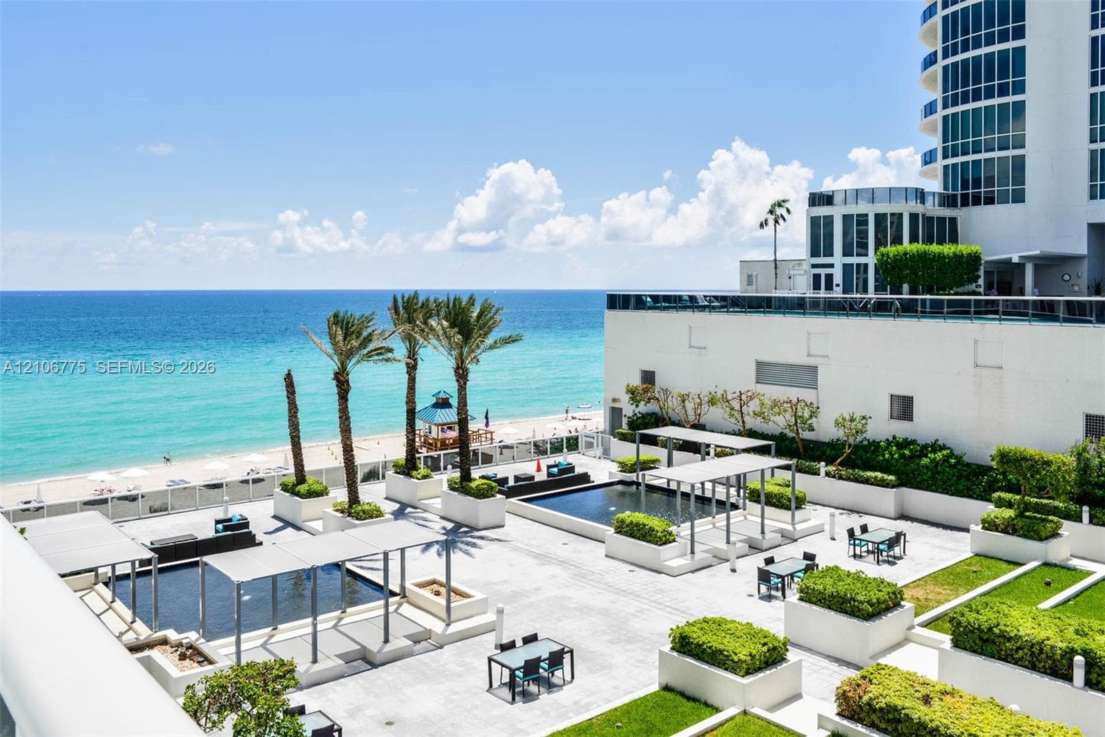 Terrace featuring reflective water elements, pergola structures, tiered landscaping with manicured shrubbery, and oceanfront exposure