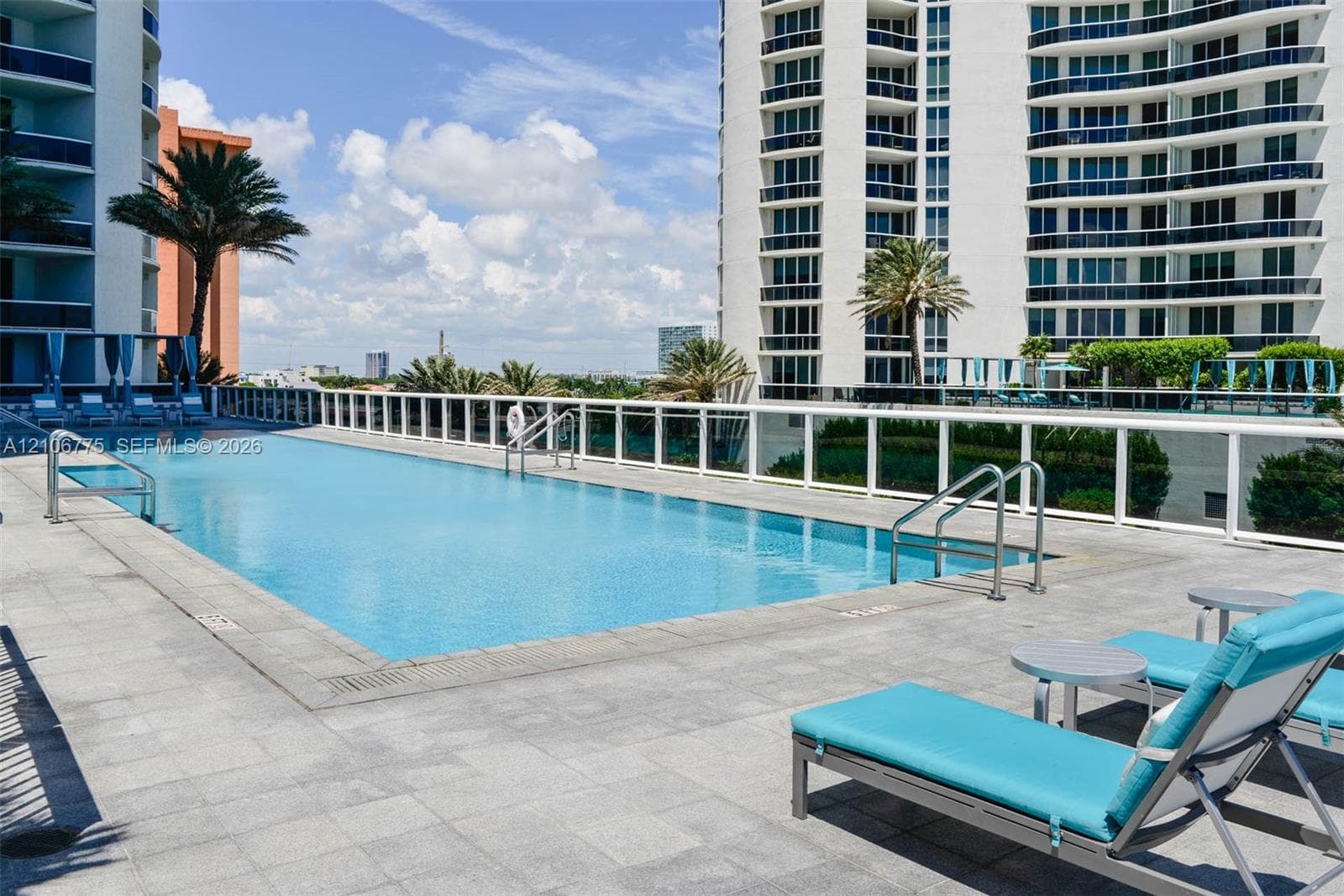 Swimming pool with perimeter metal railing and stone-tile decking