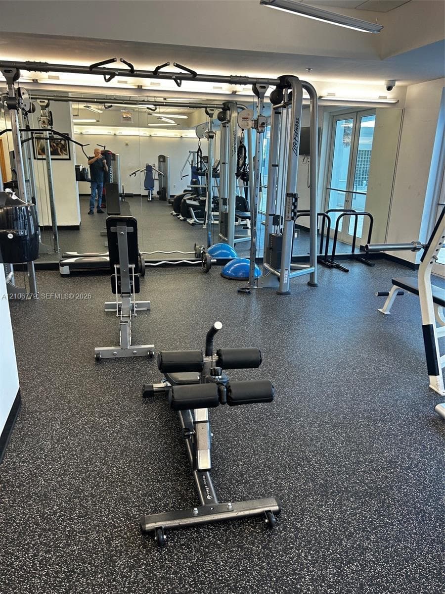 Fitness space featuring impact-resistant rubber flooring, floor-to-ceiling wall mirrors, and recessed lighting