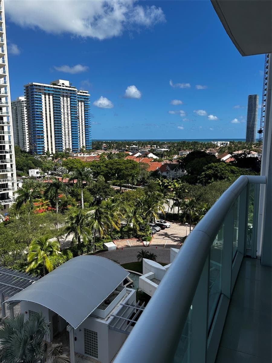 Private balcony featuring a glass-panel railing and expansive urban and ocean scenery