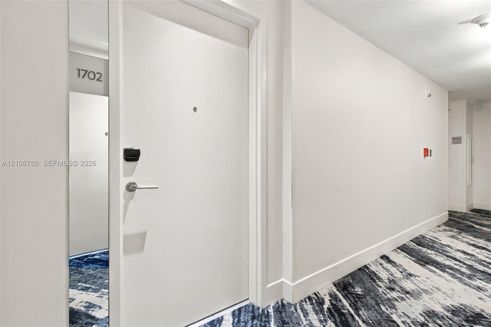 Solid core door with a matte silver lever handle, digital keypad entry, and integrated door viewer