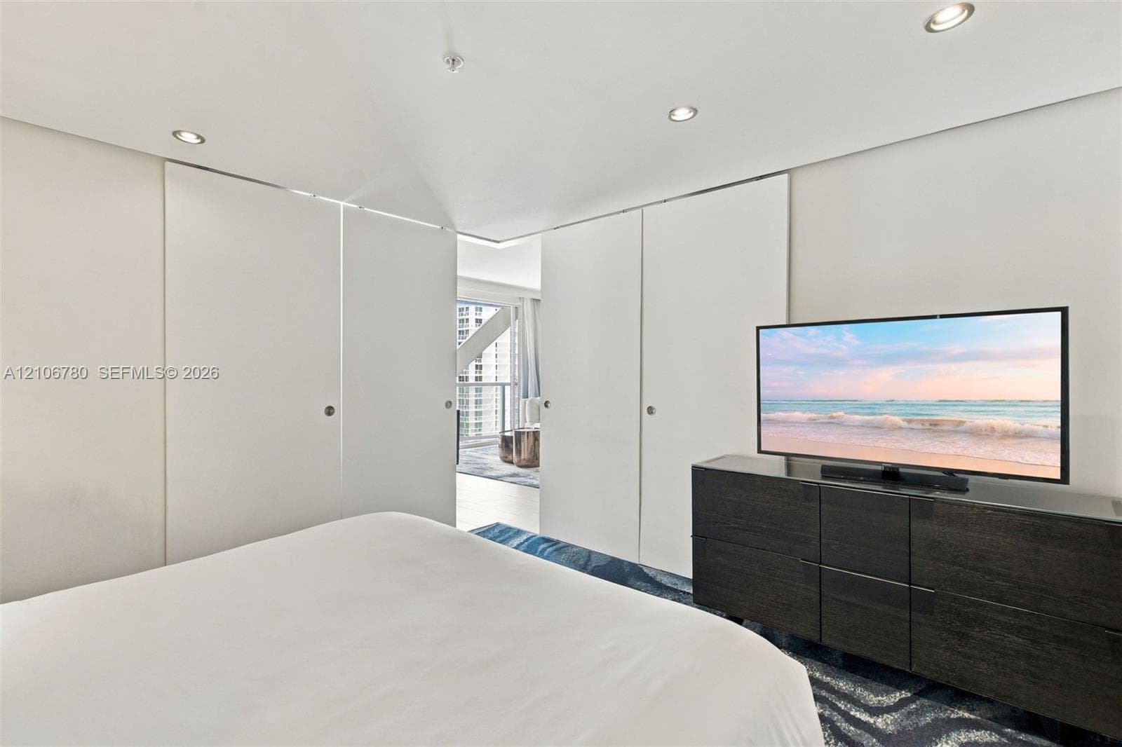 Floor-to-ceiling sliding panels, recessed lighting, and patterned floor covering