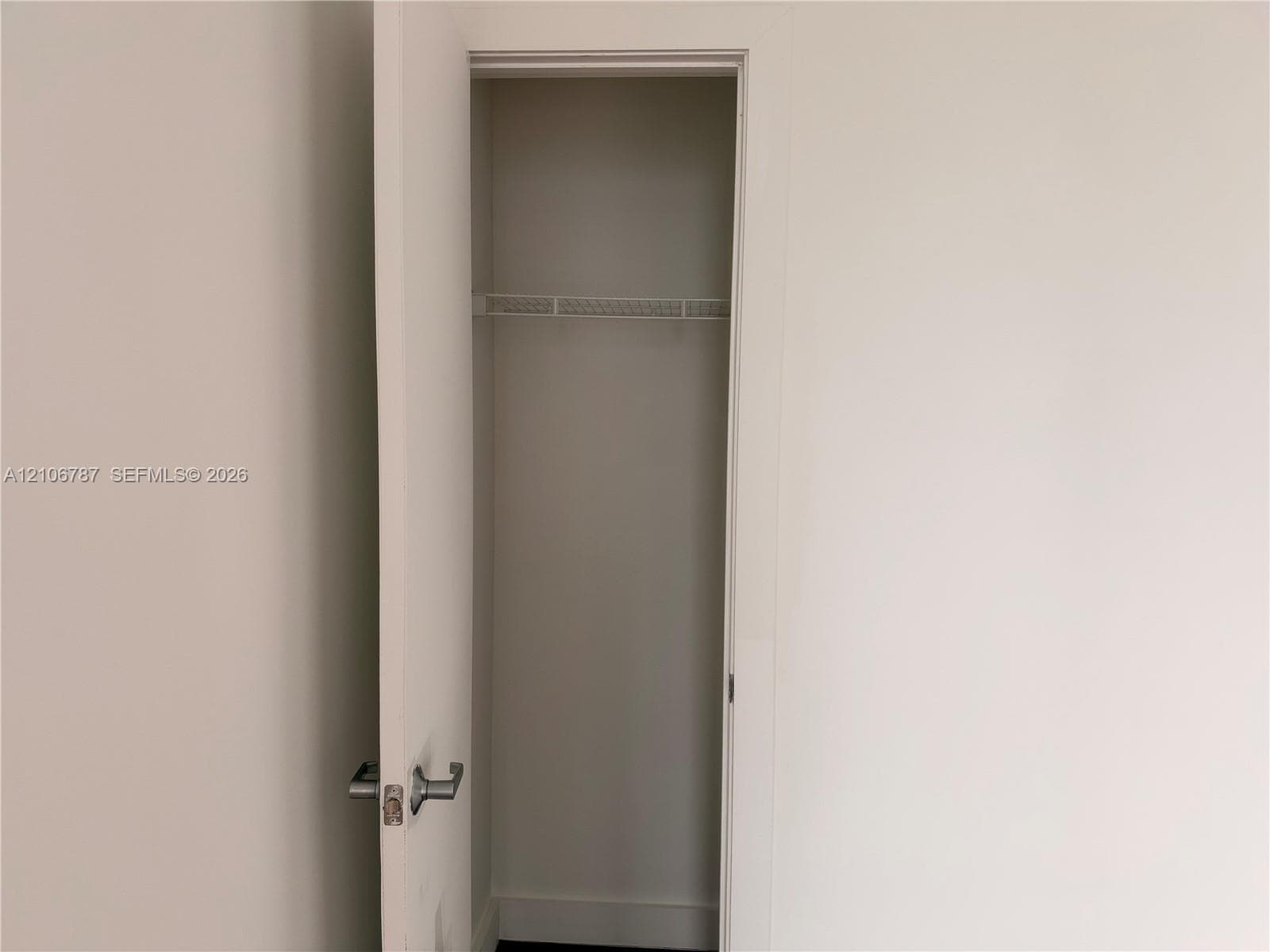 Storage closet featuring a hinged door, brushed metal hardware, and an integrated wire shelving rack