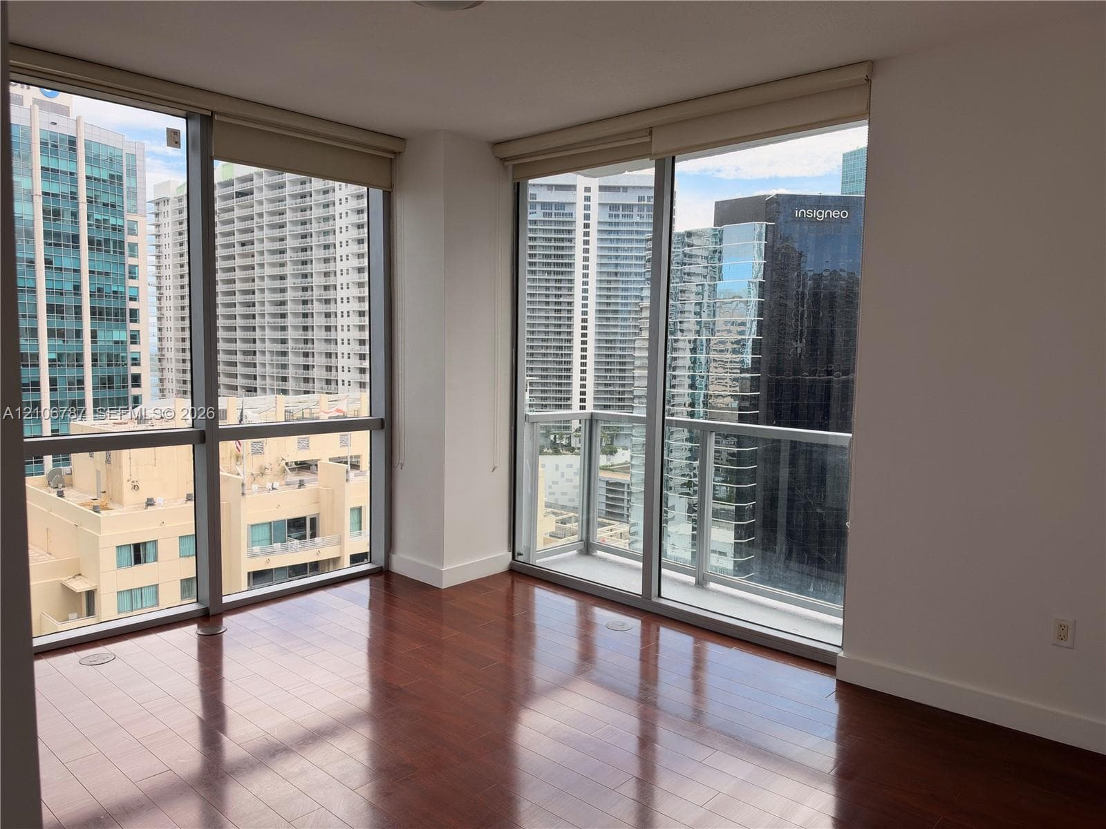 Floor-to-ceiling windows, wood-finish flooring, and an attached glass-railing balcony