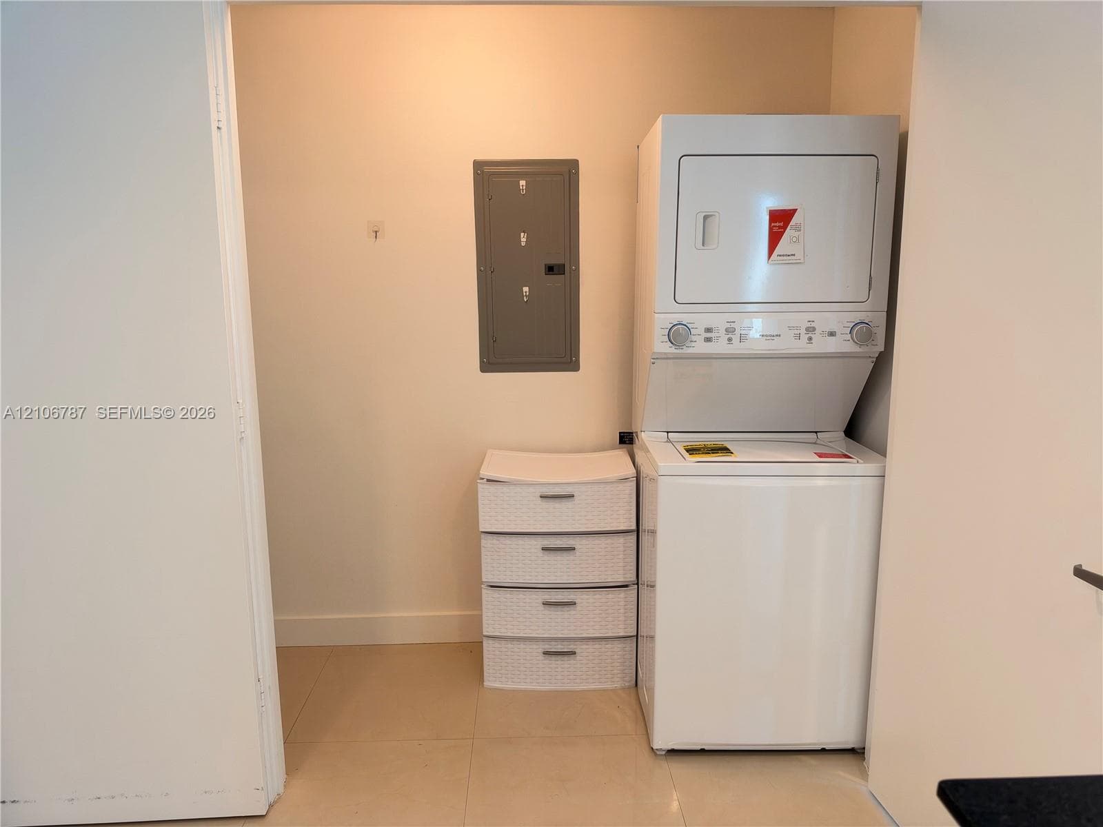 Dedicated laundry nook featuring a stacked washer and dryer unit and a recessed electrical service panel