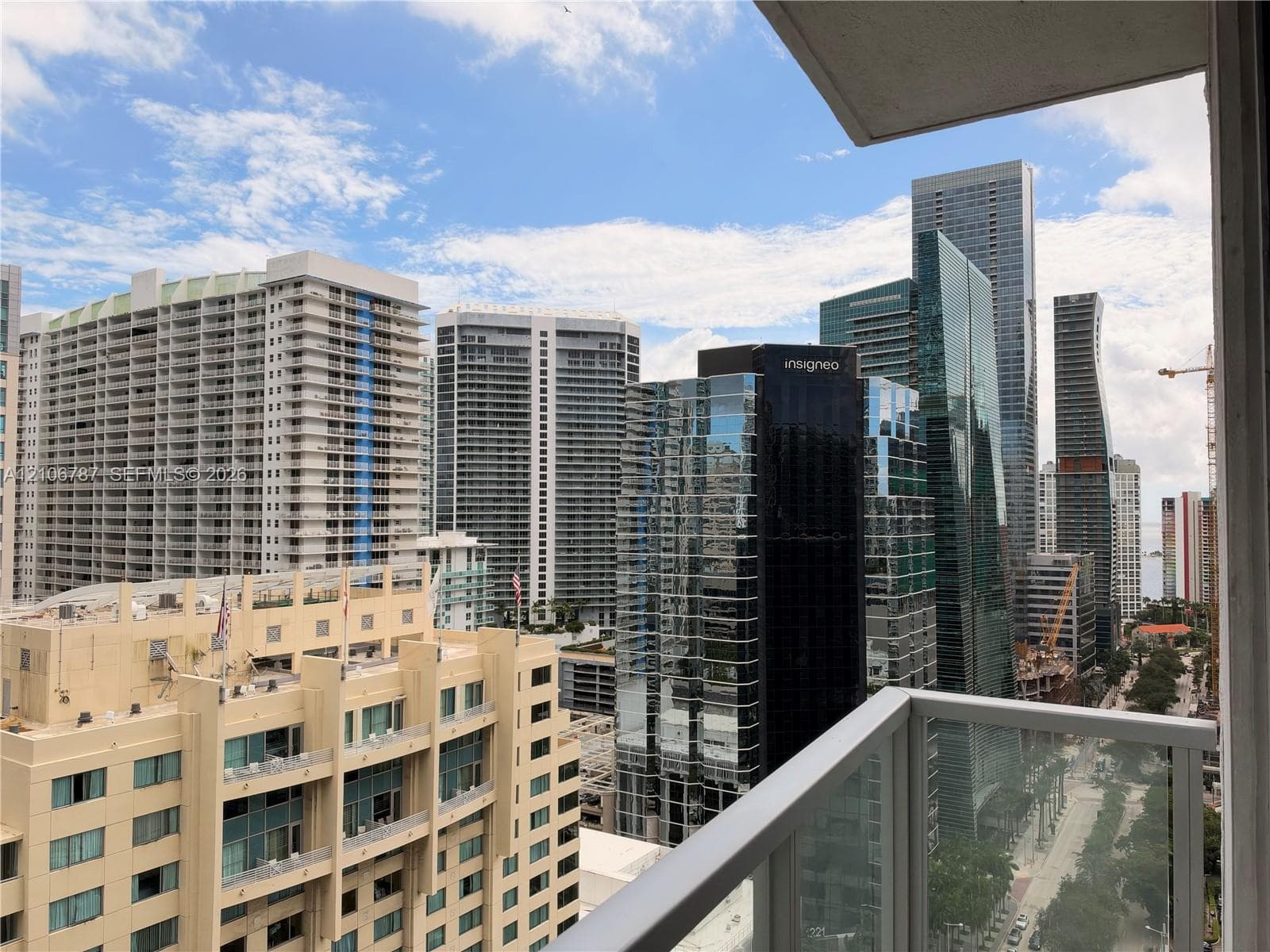 Private balcony with glass and metal railing overlooking a high-density urban cityscape