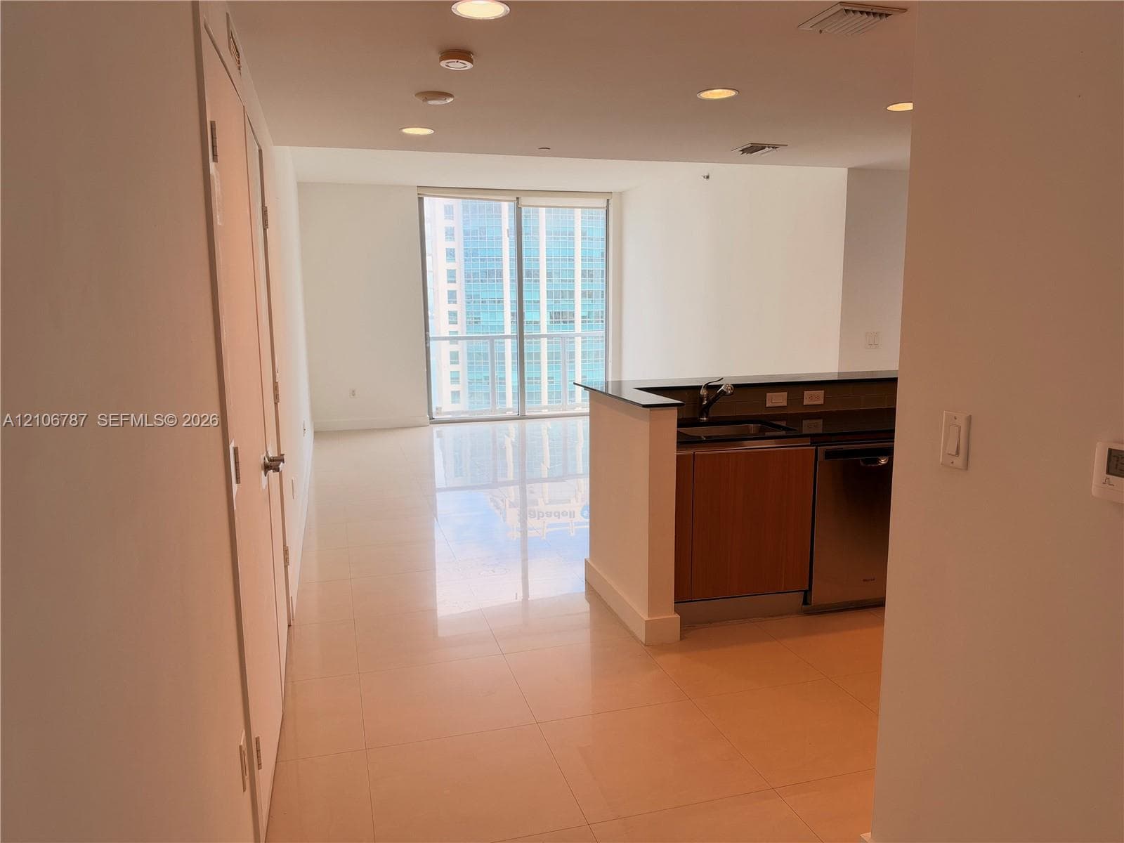 Kitchen area featuring a peninsula with a dark stone countertop, flat-panel wood-finish cabinetry, stainless steel appliances, and tile flooring throughout
