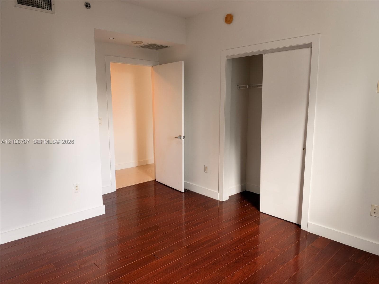 Room featuring wood-finish flooring, a built-in closet with sliding doors, and solid-core interior doors