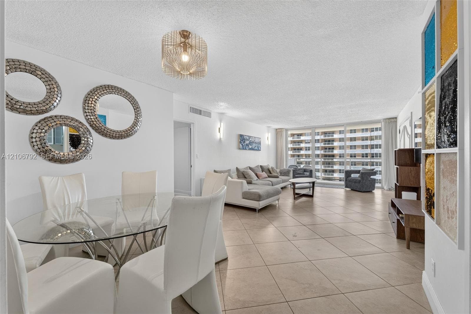 Open-concept floor plan featuring large-format ceramic tile flooring, floor-to-ceiling windows, and decorative multi-panel wall accent