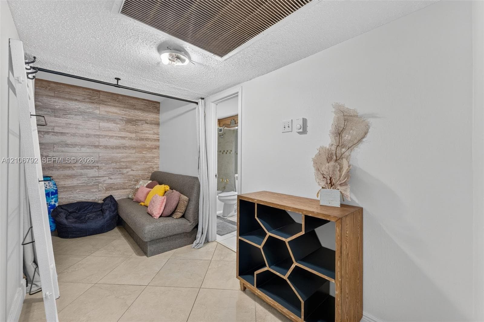 Room featuring large-format diagonal tile flooring, wood-finish wall paneling, and ceiling-mounted track hardware