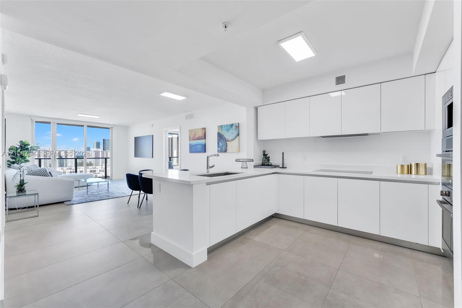 Kitchen featuring white high-gloss cabinetry, stone countertops, stainless steel appliances, and large-format tile flooring, complemented by floor-to-ceiling glass panel windows