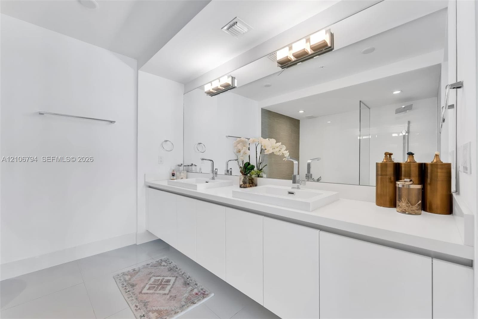 Floating dual-sink vanity with a solid surface countertop, two rectangular vessel sinks, polished chrome fixtures, and a wall-to-wall mirror with integrated lighting