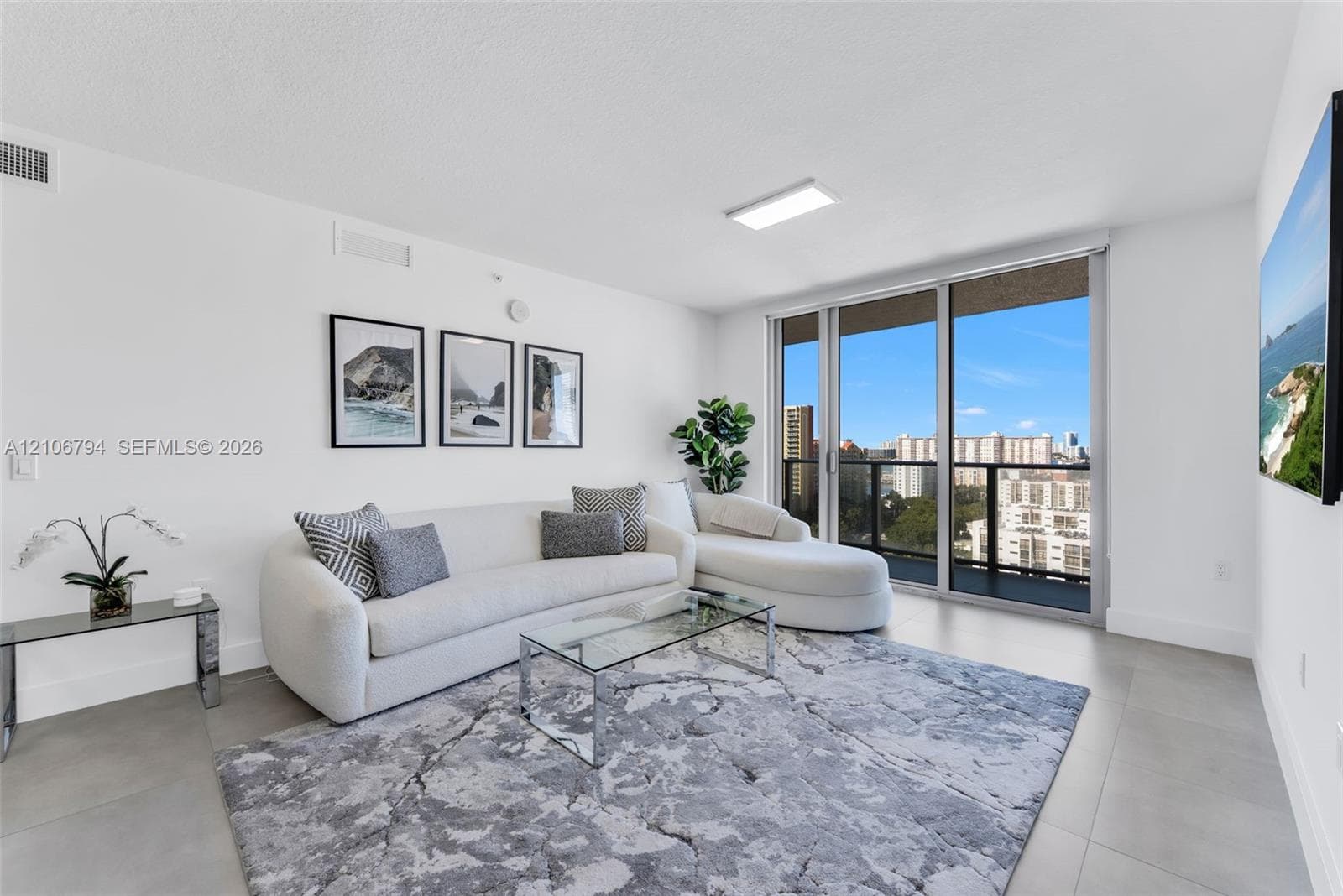 Neutral-toned tile flooring, floor-to-ceiling glass paneling, and a private balcony featuring a black metal railing