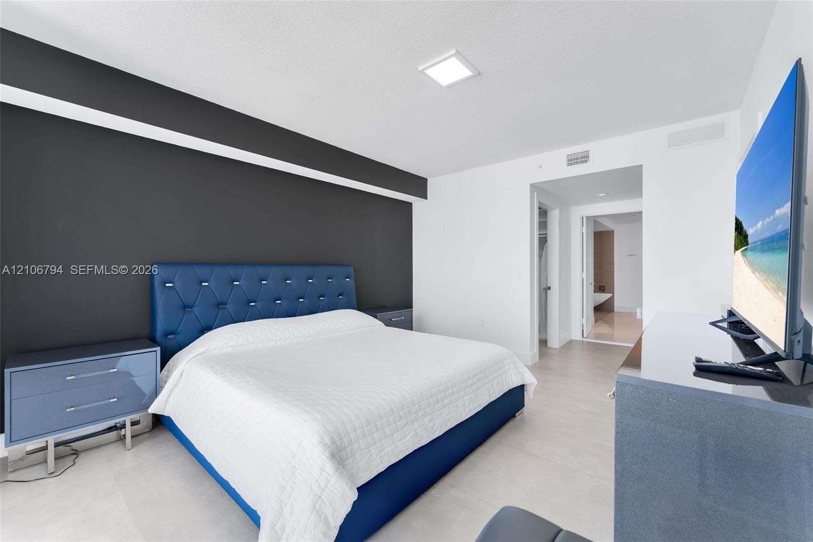 Neutral-toned interior space featuring a dark accent wall, large-format tile flooring, and a flush-mount ceiling light fixture
