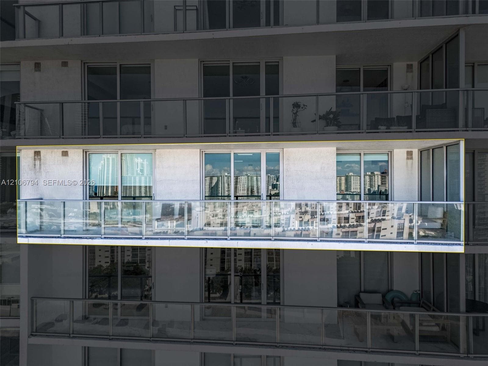 Extended private balcony featuring a transparent glass railing and sliding glass door access