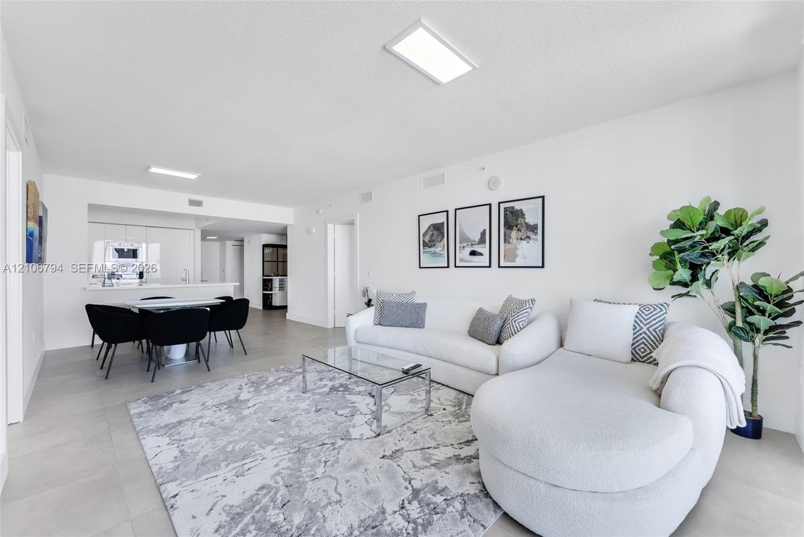 Open-concept interior featuring large-format tile flooring, recessed rectangular ceiling lighting, and a breakfast bar counter