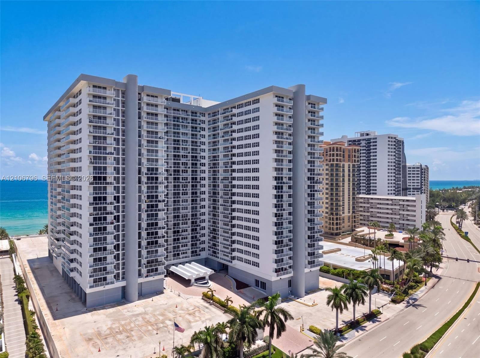 High-rise residential exterior featuring wrap-around balconies, a multi-tiered concrete facade, and a covered porte-cochère entrance