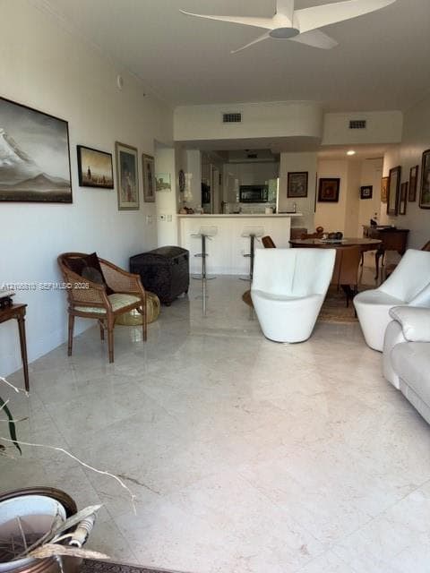 Open-concept area featuring stone flooring, a multi-blade ceiling fan, and a breakfast bar with integrated cabinetry