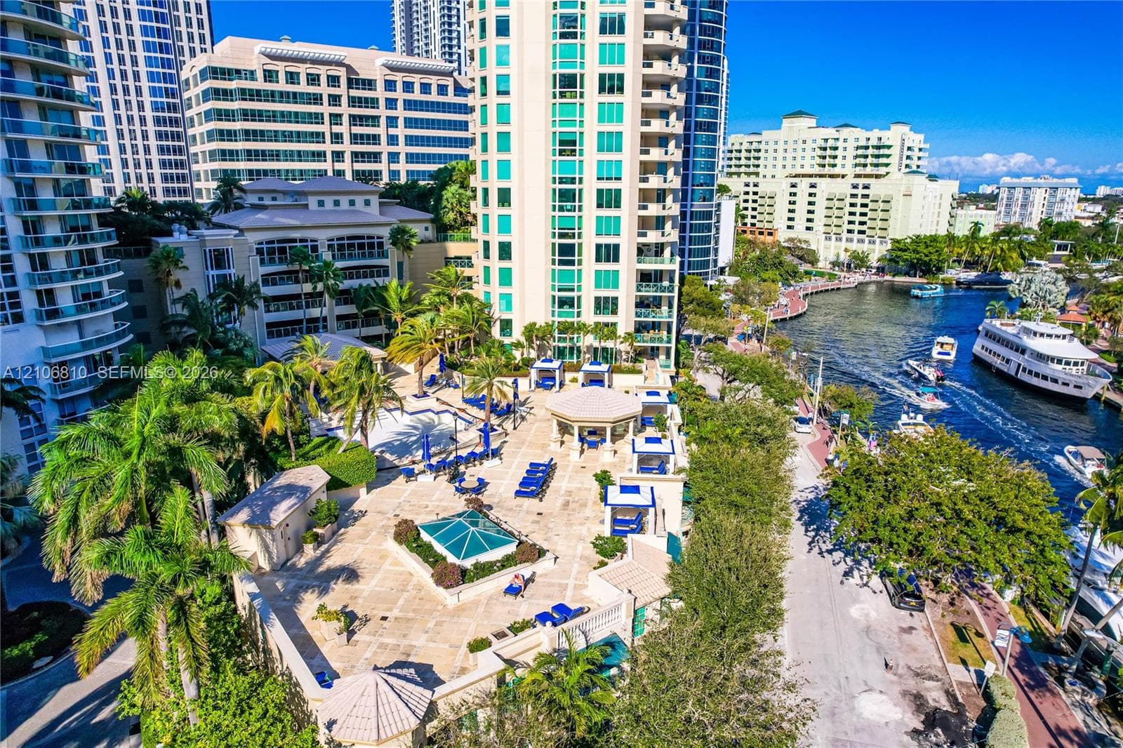 High-rise urban community featuring paved outdoor terrace space, swimming pool, gazebo, mature landscaping, and waterfront access