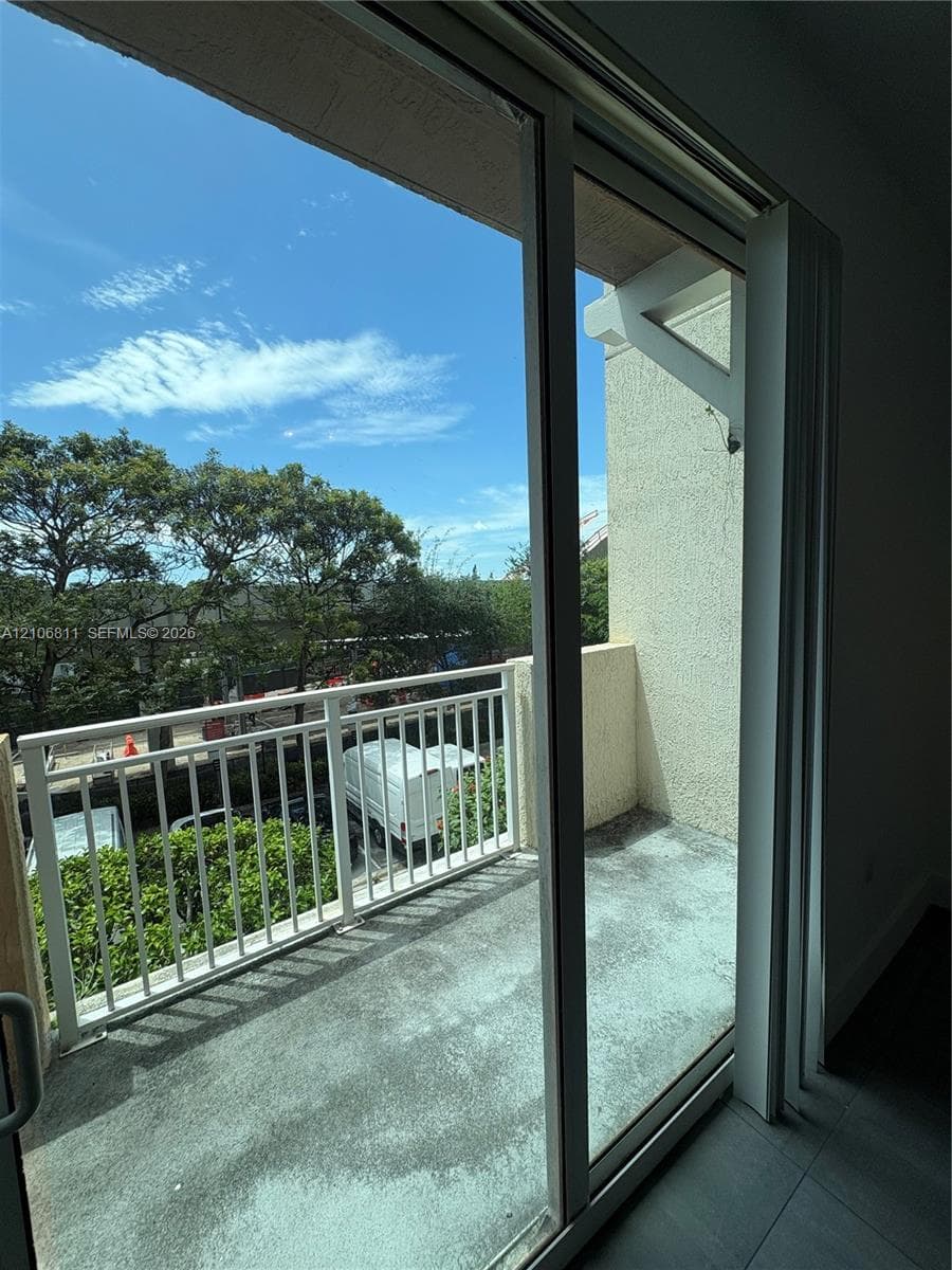 Private balcony featuring concrete flooring, a white metal railing, and stucco exterior wall finish