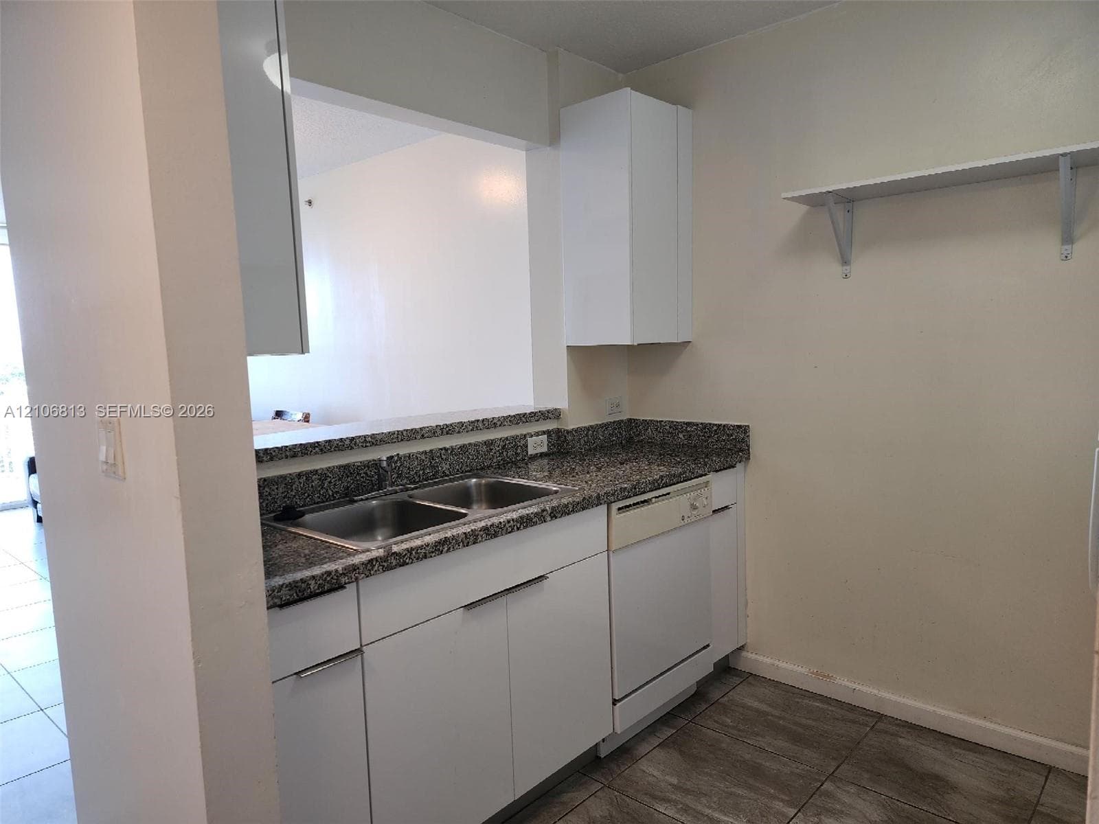 Kitchen featuring white cabinetry, stone-finish countertops, an integrated double-basin stainless steel sink, a dishwasher, and tiled flooring