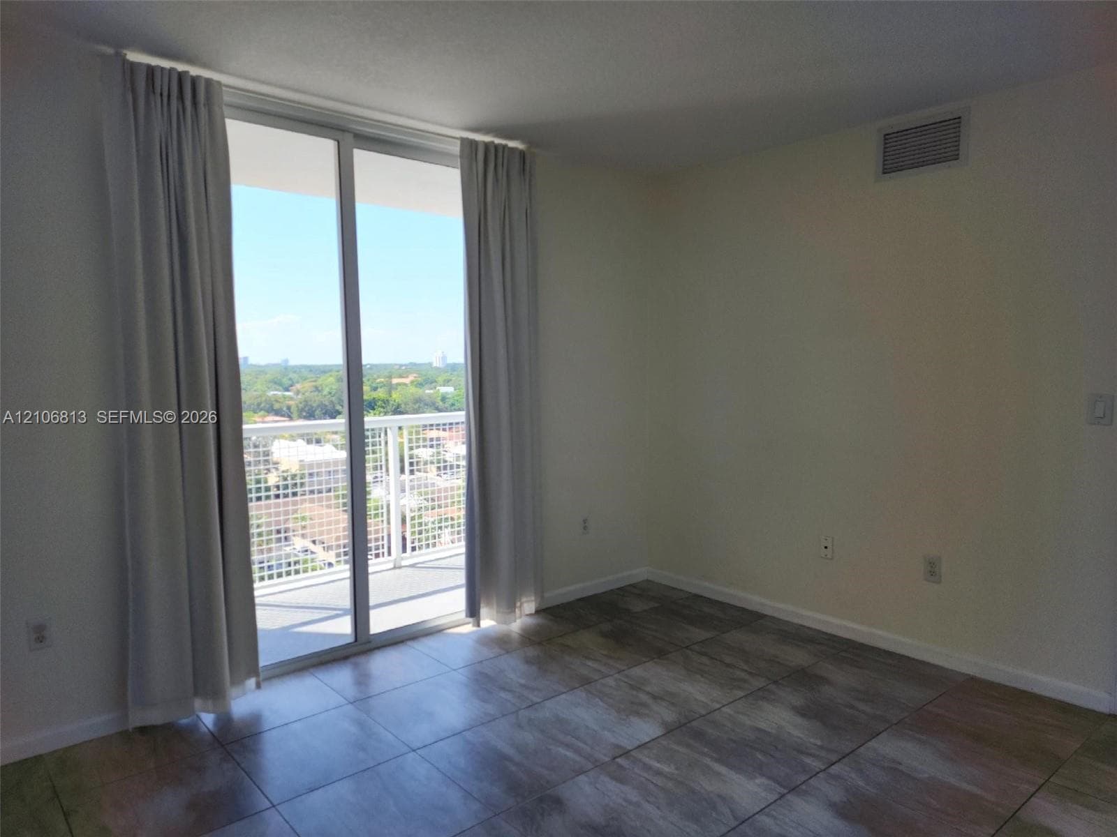 Large-format tile flooring, floor-to-ceiling glass sliding doors, and private balcony with metal railing