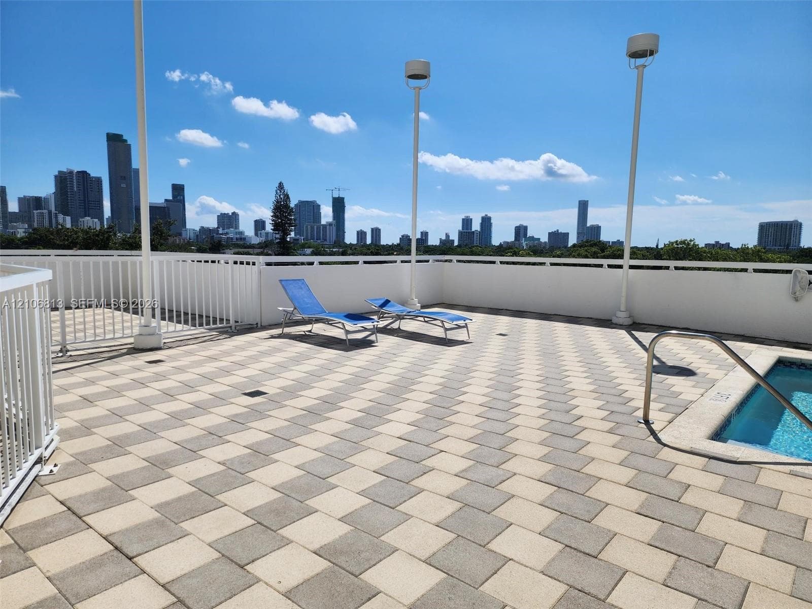 Rooftop terrace featuring a tiled deck, perimeter metal railing, integrated lighting, and a built-in spa