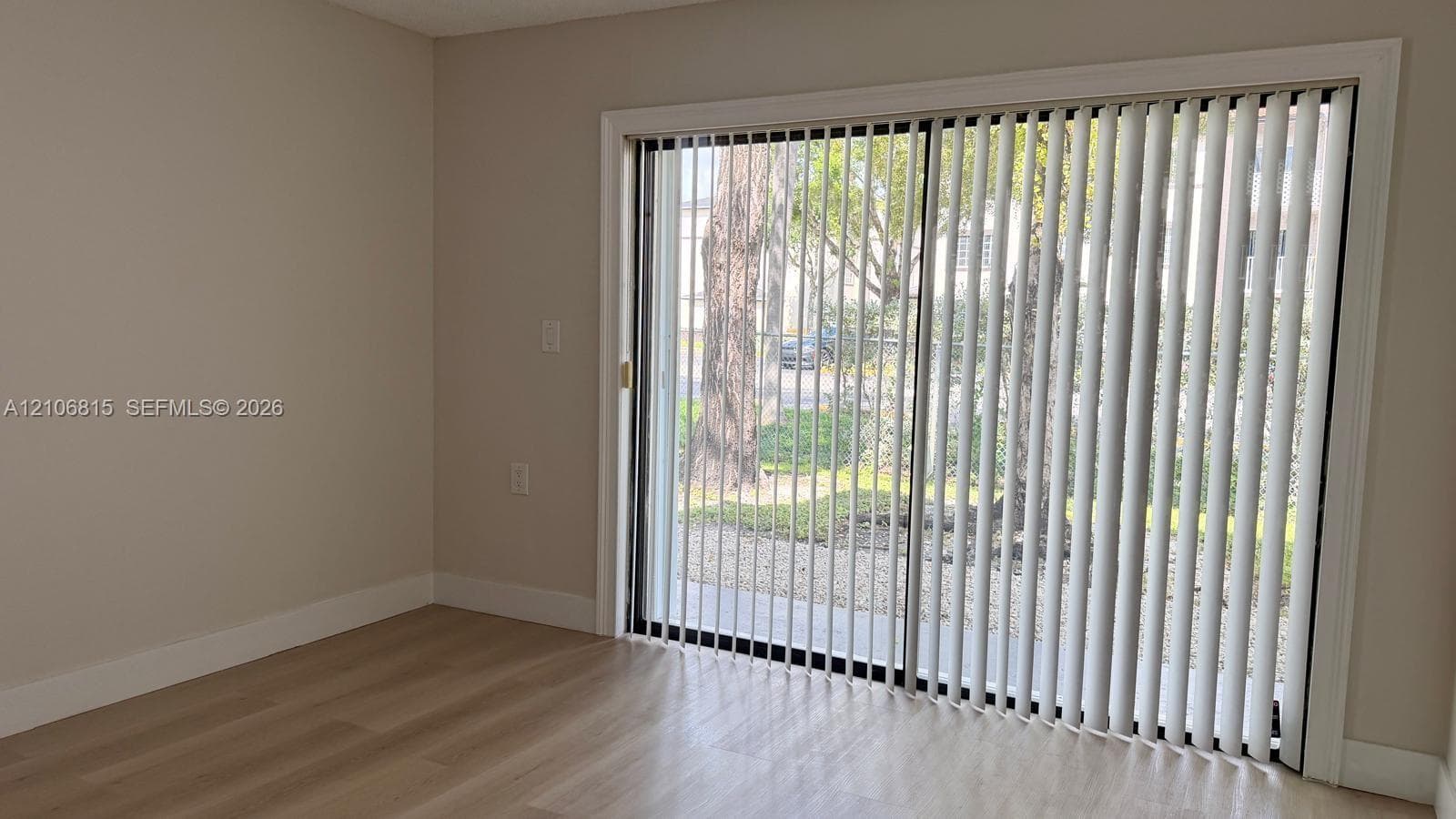 Sliding glass doors with vertical blinds and light-toned wood-finish flooring