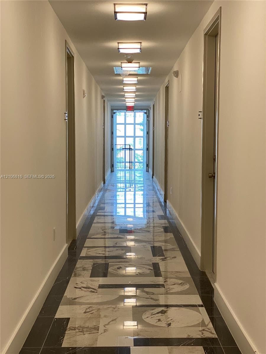Hallway featuring geometric tile flooring with a high-gloss finish, flush-mount ceiling lighting, and a multi-pane glass door