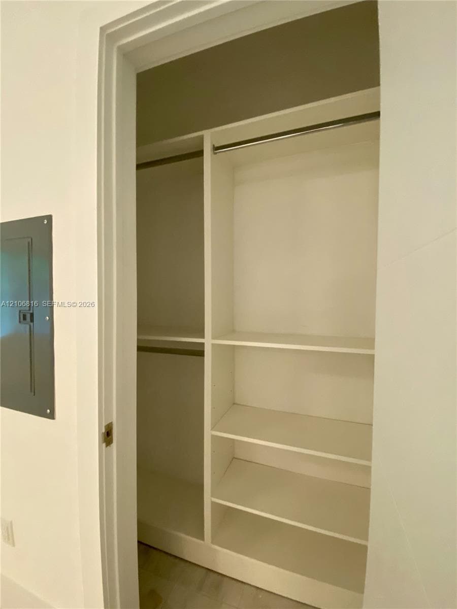 Built-in closet featuring white shelving, integrated clothing rods, and matte-finish dividers