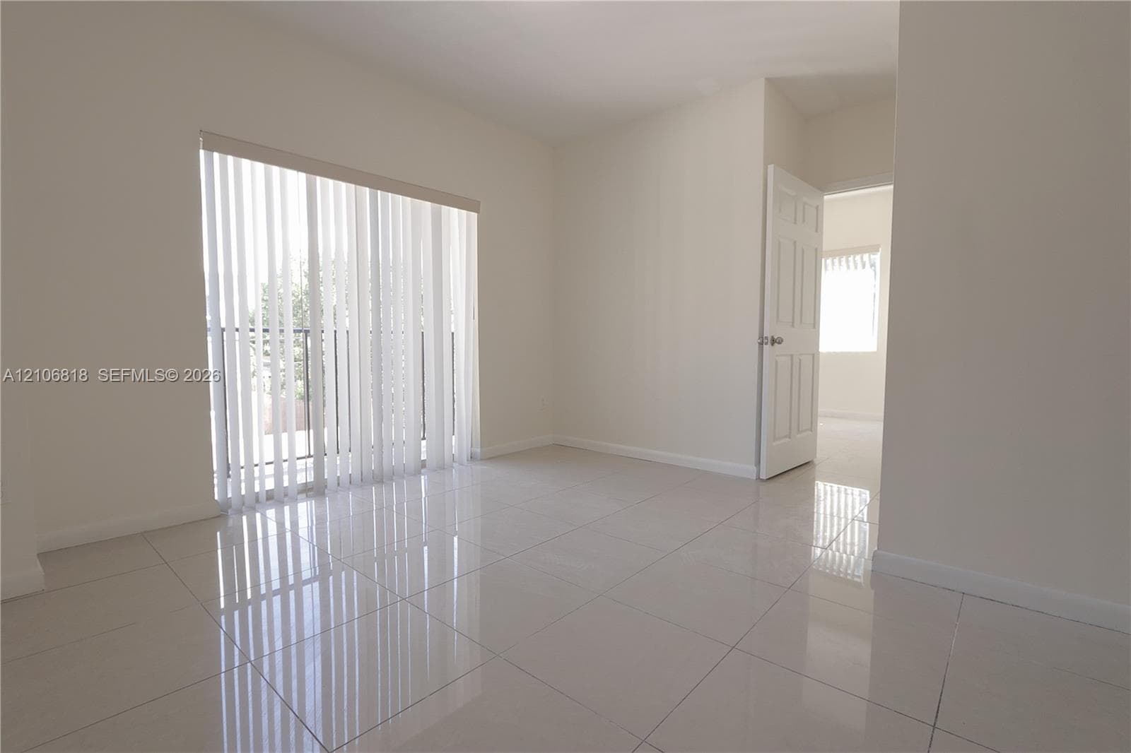 Neutral-toned room featuring large-format ceramic tile flooring, a glass sliding door, and a six-panel interior door