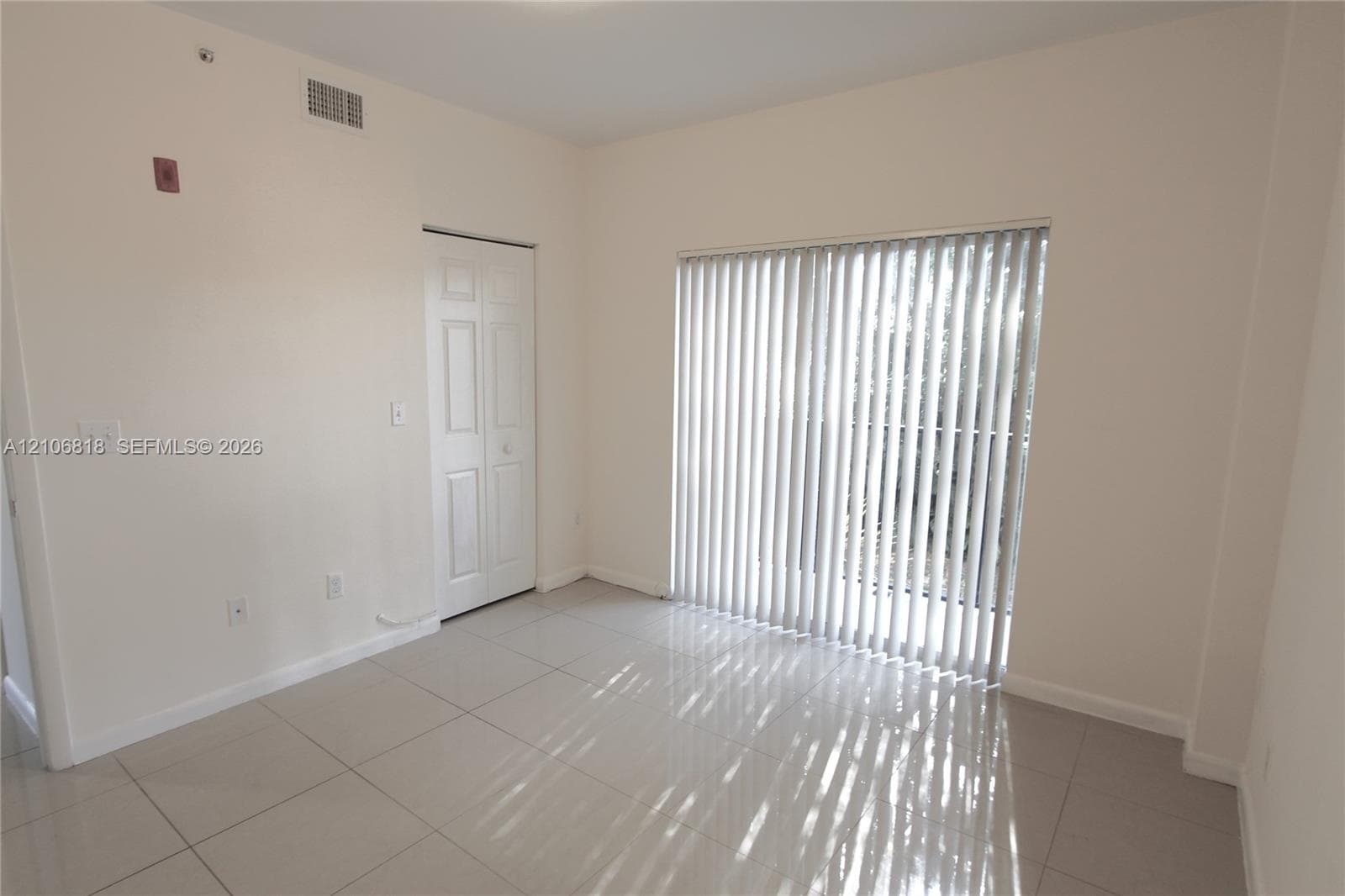 Interior space featuring large-format ceramic tile flooring, vertical window blinds, and a bi-fold closet door
