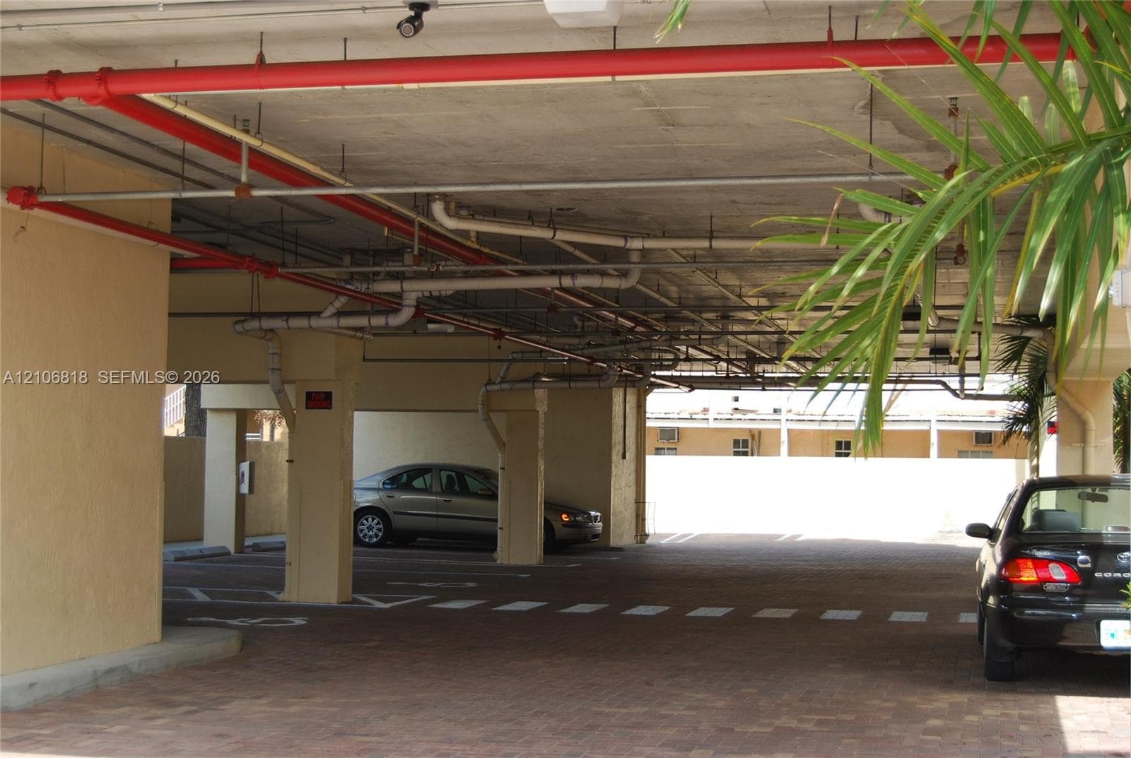 Covered parking area featuring paver flooring, structural columns, and an integrated overhead fire suppression system