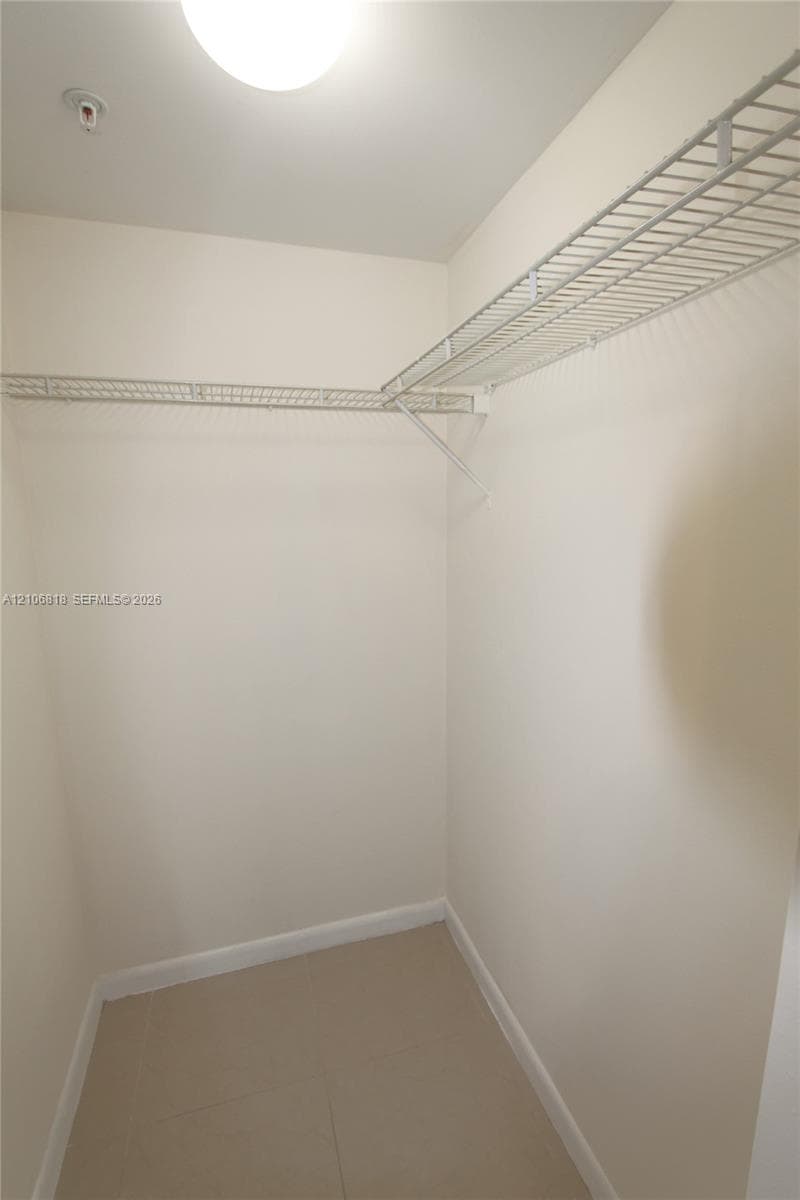 Storage area featuring wall-mounted wire shelving and tile flooring