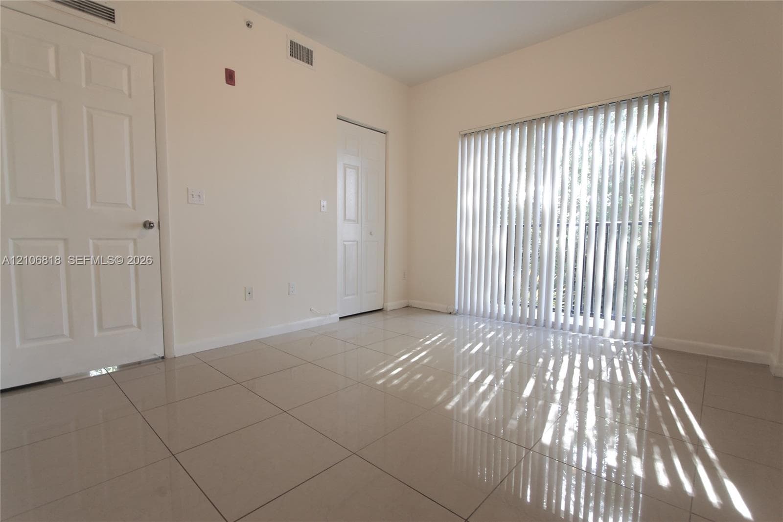 Interior room featuring large-format tile flooring, vertical window blinds, and two six-panel interior doors