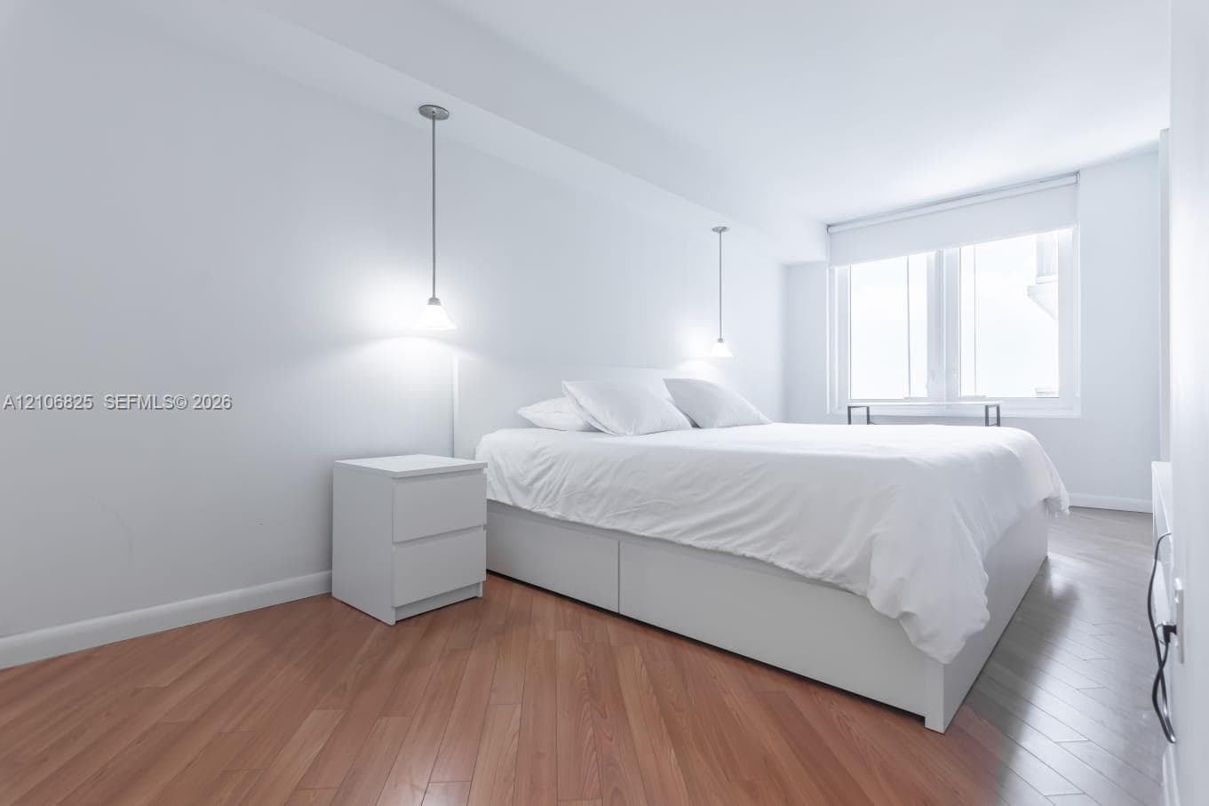 Bedroom featuring wood-finish flooring, recessed window, and dual pendant light fixtures