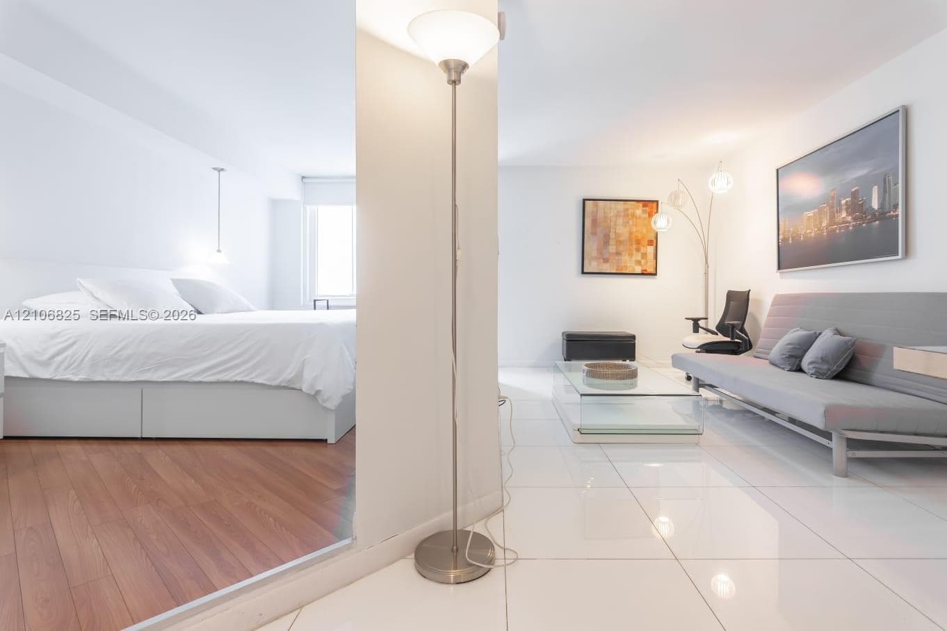Open-concept interior featuring large-format white tile flooring, wood-finish flooring, a central partition wall, and neutral wall tones
