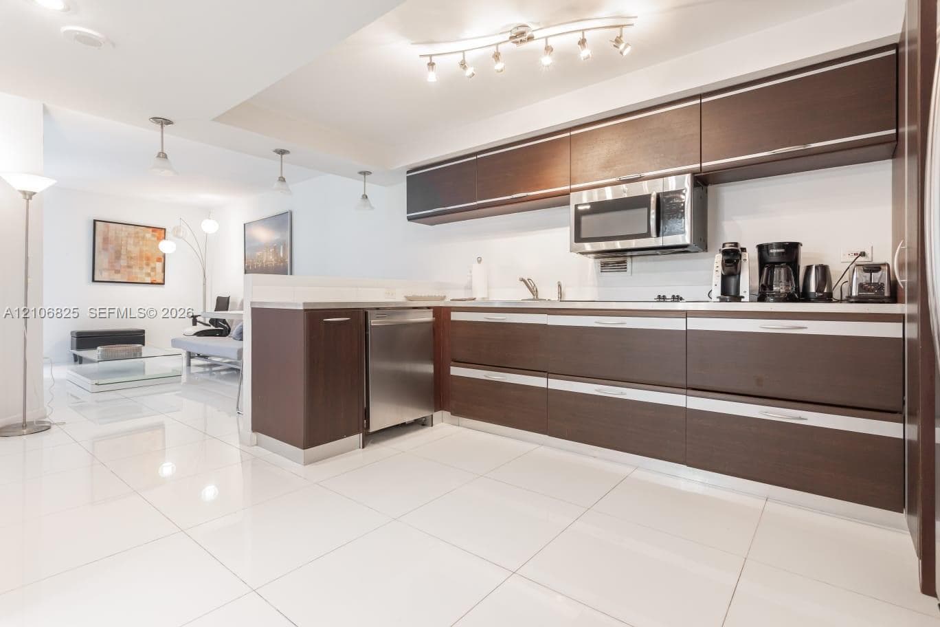 Kitchen featuring espresso-toned flat-panel cabinetry, stainless steel appliances, polished tile flooring, and multi-light track lighting