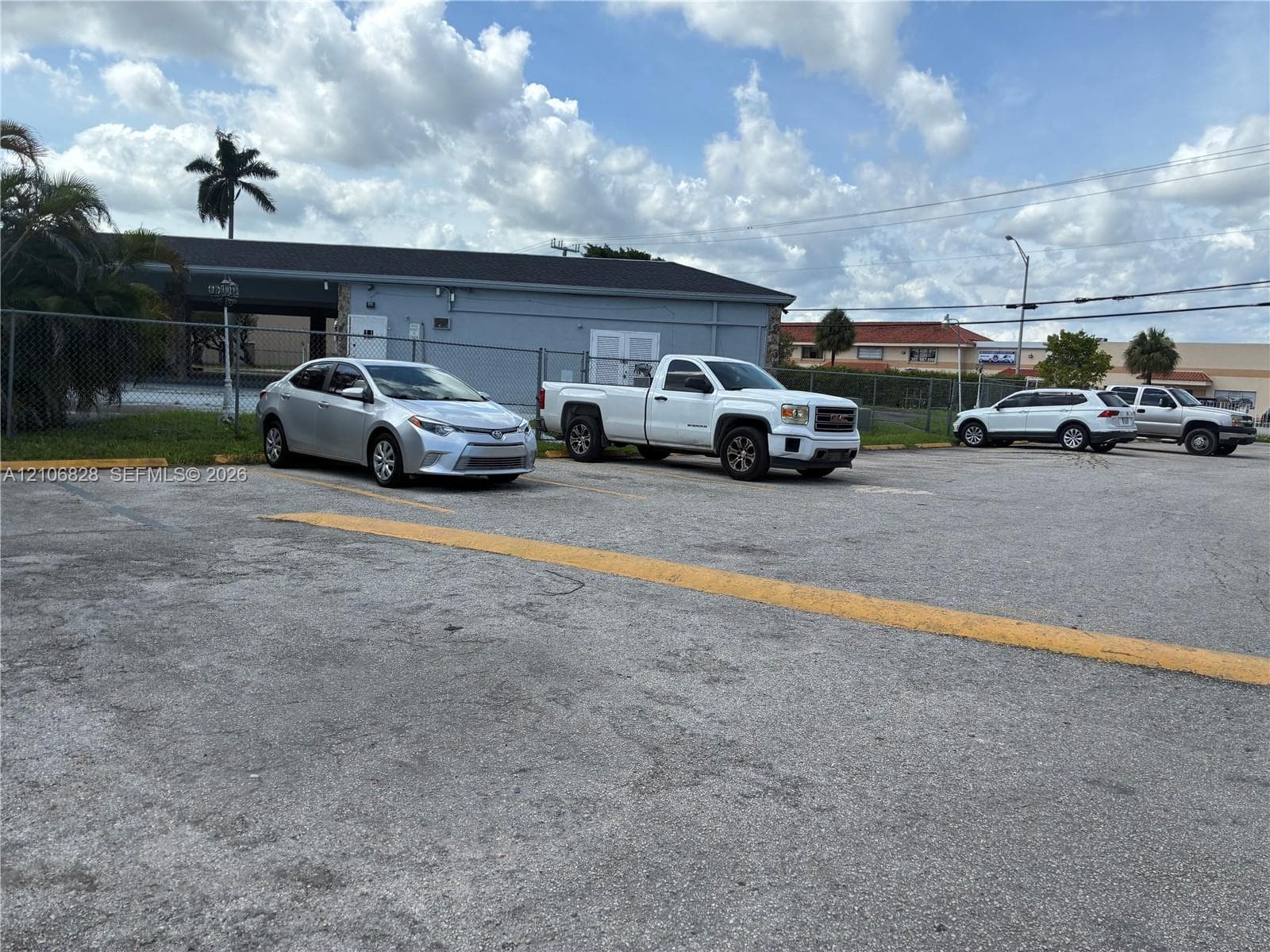 Asphalt-paved parking lot with designated yellow line striping and perimeter chain-link fencing