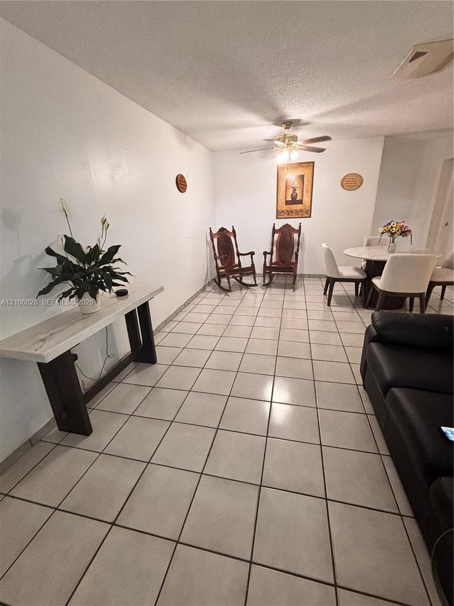 Neutral-toned square tile flooring throughout and ceiling-mounted fan with light fixture