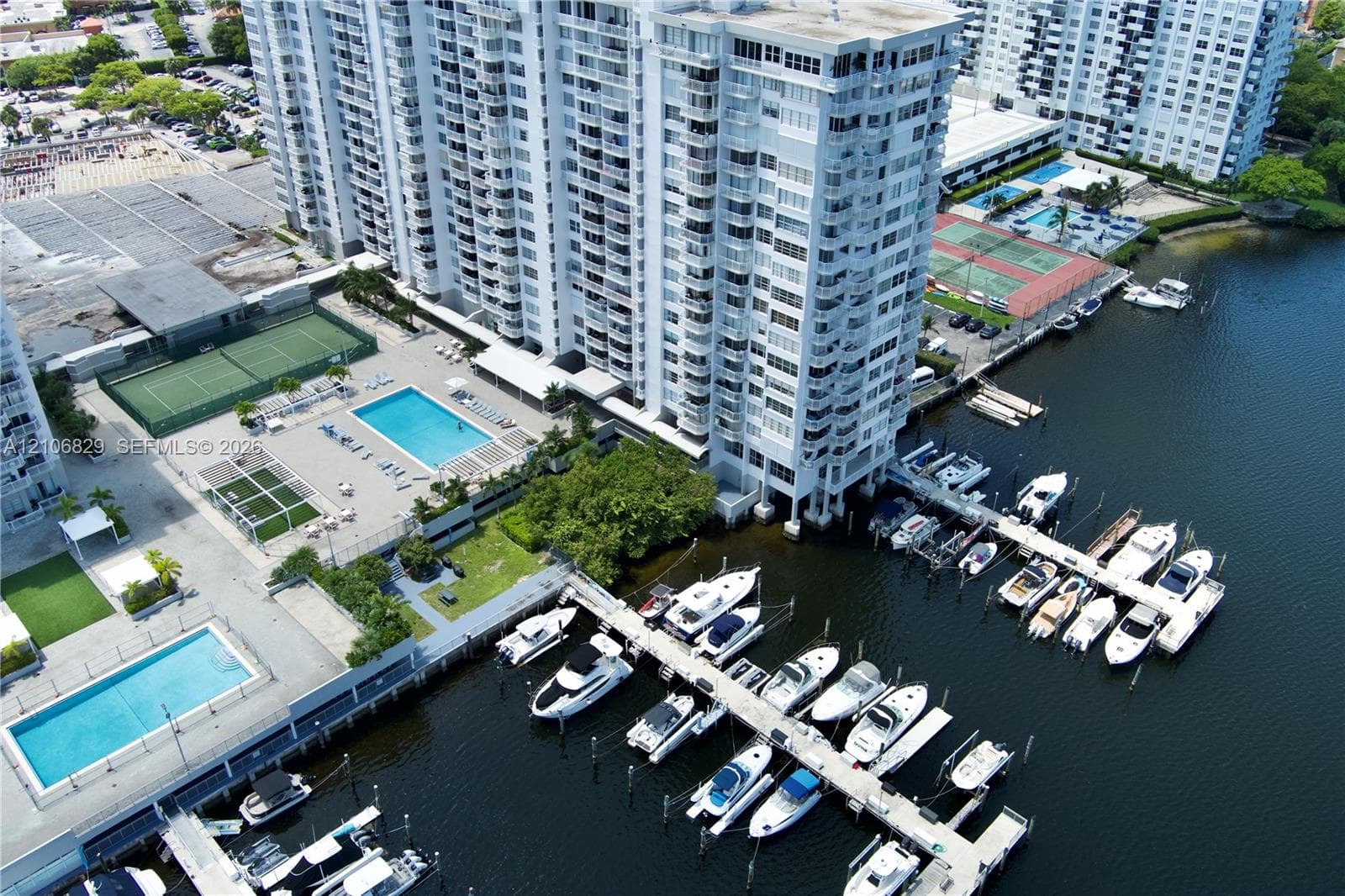 High-rise residential building featuring an on-site marina with boat slips, multiple swimming pools, tennis courts, and landscaped grounds