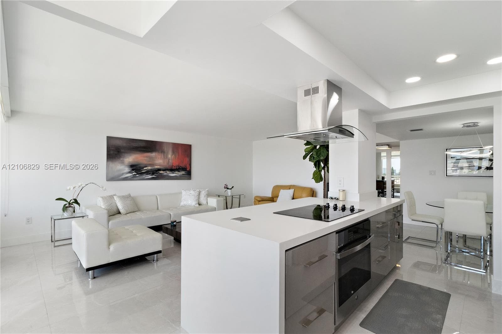 Kitchen island featuring stone countertops, integrated electric cooktop, stainless steel ventilation hood, and high-gloss cabinetry