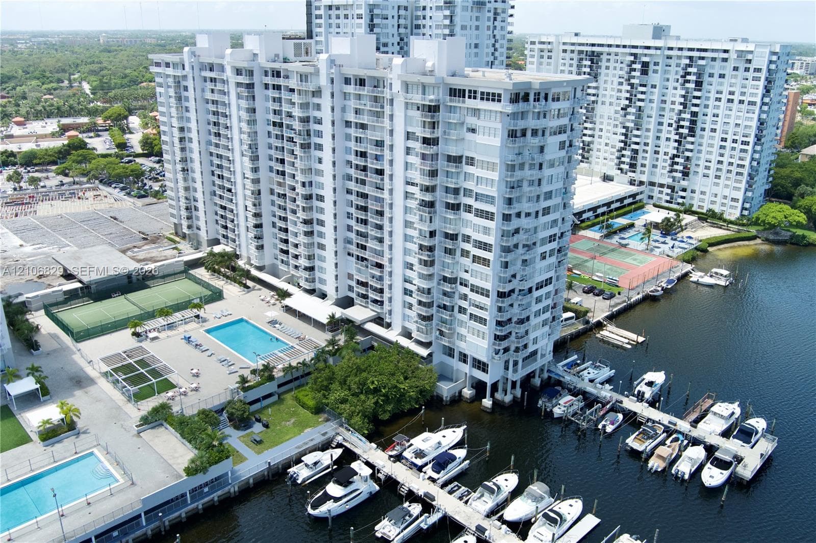 High-rise residential complex featuring a private marina with multiple boat slips, two outdoor swimming pools, and dual tennis courts