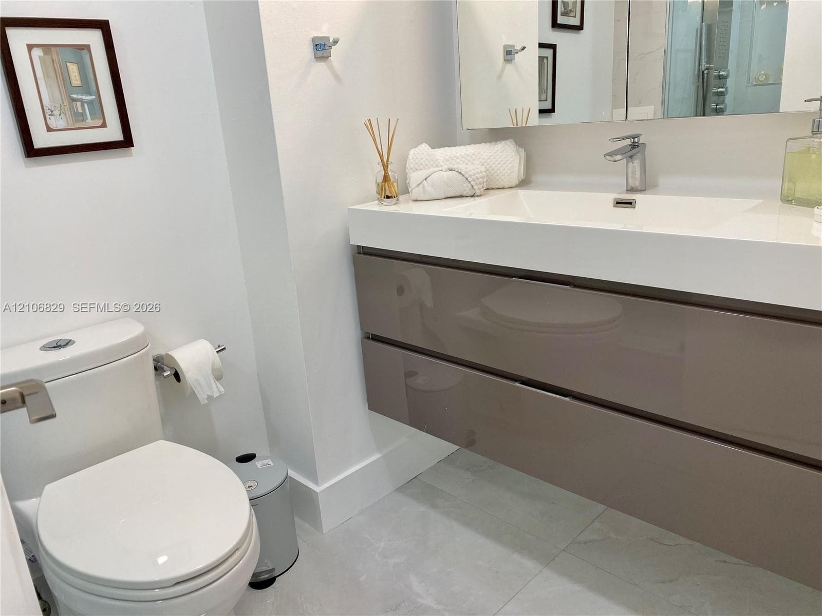 Floating vanity with high-gloss cabinetry, integrated sink basin, chrome single-handle faucet, and large-format tile flooring