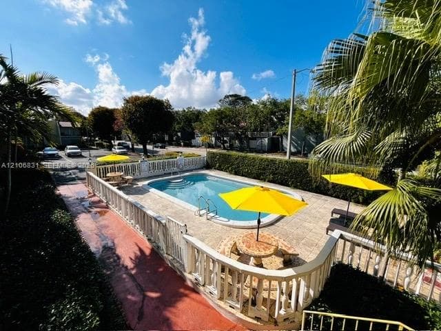 In-ground pool with integrated steps, surrounded by stone-finish decking and a balustrade perimeter fence, featuring mature landscaping