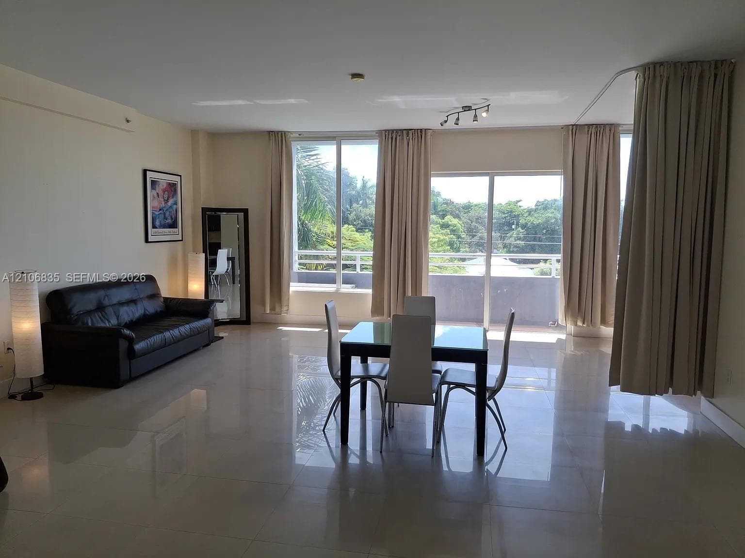 Open-concept floor plan with polished tile flooring, floor-to-ceiling windows, and access to a private balcony